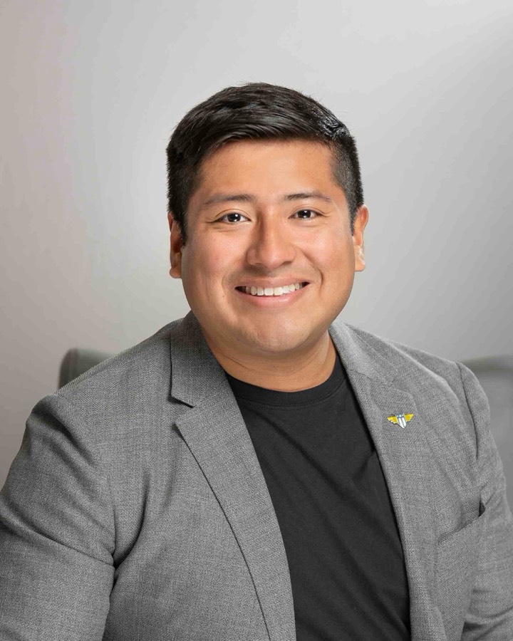 Javier Dutan smiling, in a grey blazer over a black T-shirt